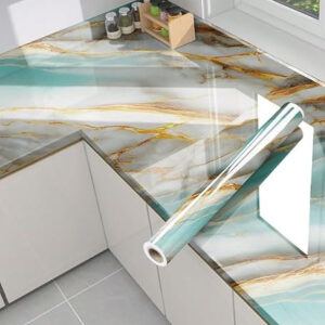 A roll of self-adhesive contact paper with a glossy, sky-blue marble and gold-vein pattern, shown partially applied to a modern kitchen countertop.